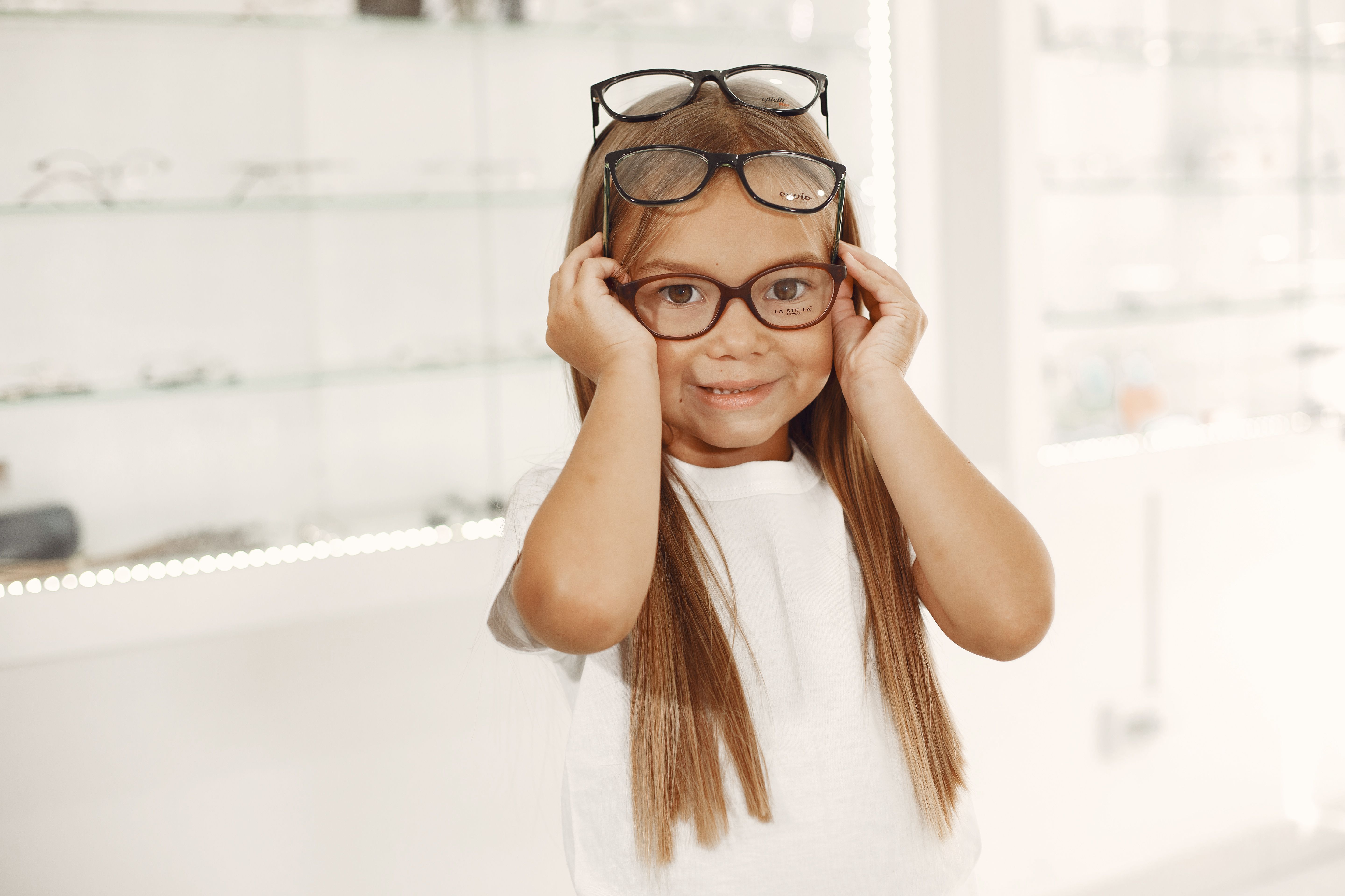 Child trying on several pairs of glasses during an eye examination for childhood myopia